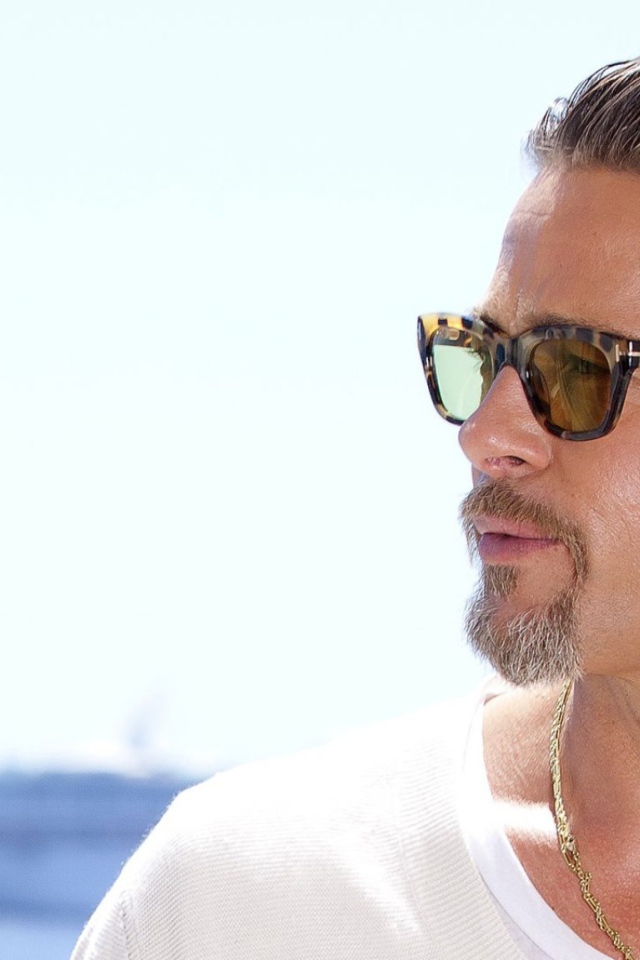 Актер Брэд Питт в очках на фоне океана