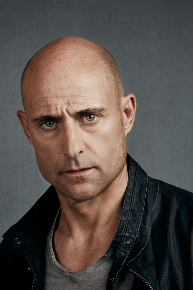 Марк Стронг в черной куртке на сером фоне