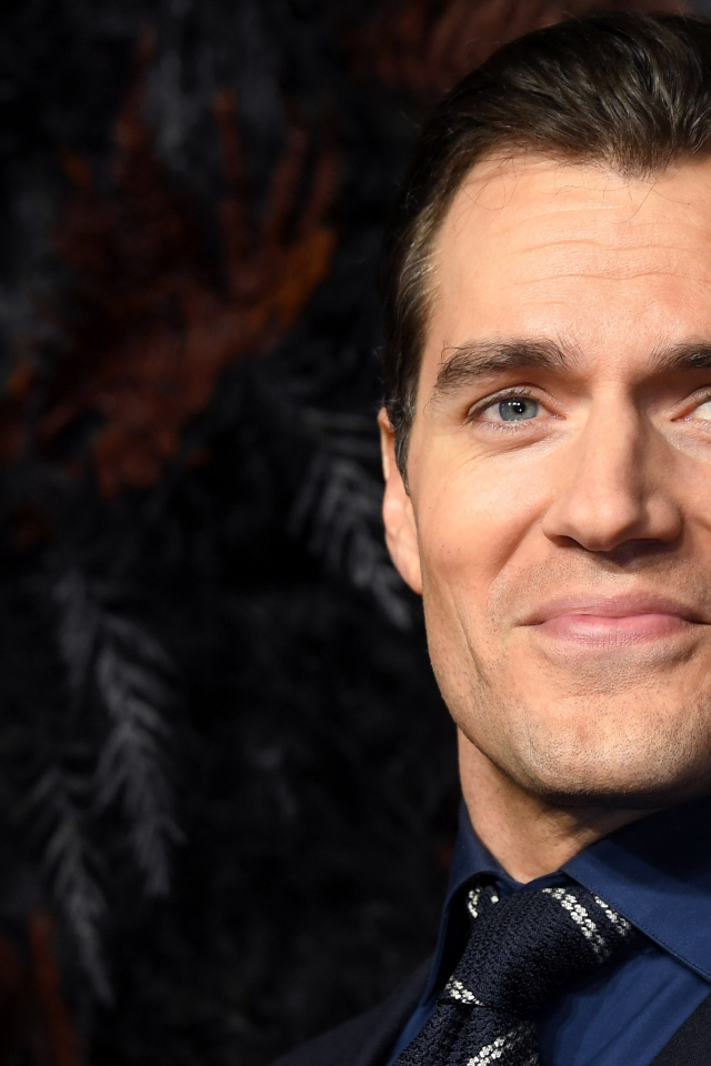 Улыбающийся актер Генри Кавилл в костюме