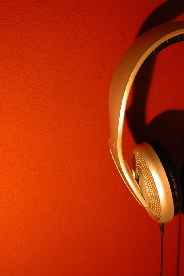 Большие золотые наушники на оранжевом фоне 