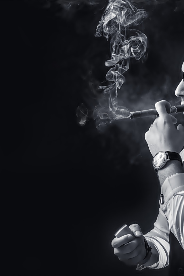Мужчина с сигарой в руке на черном фоне 