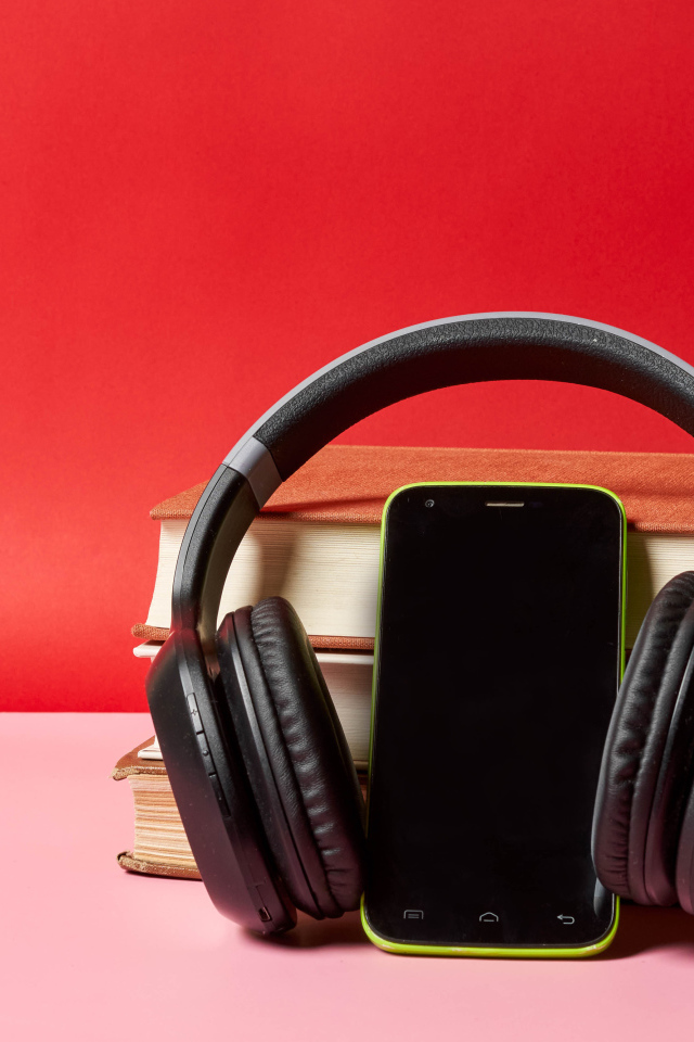 Смартфон, наушники и книги на красном фоне