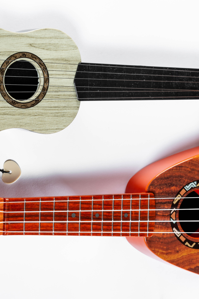 Две маленькие гитары укулеле на белом фоне