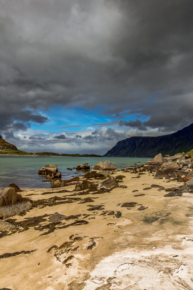 Большие камни на берегу фьорда под грозовым небом 