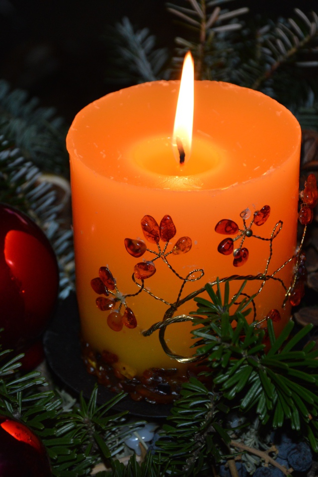 Зажженная свеча с ветками ели 