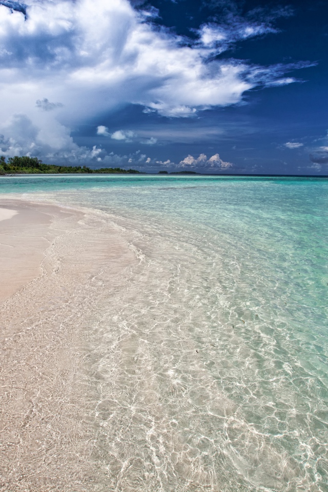 Чистая голубая вода на пляже с желтым песком