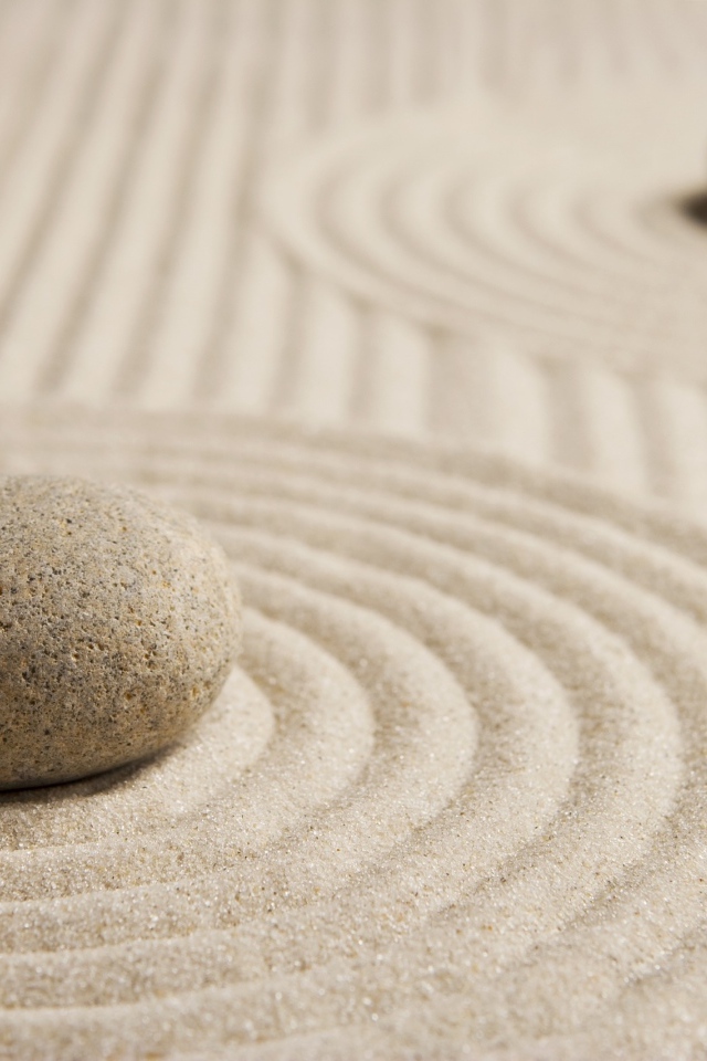 Большой серый камень на песке с кругами 