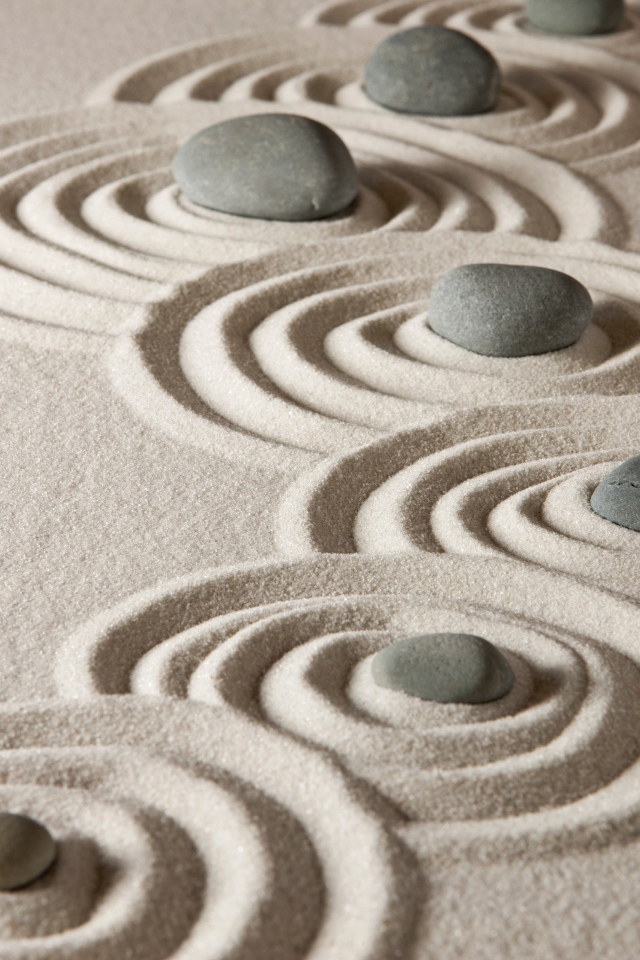 Маленькие серые камни с кругами на песке 