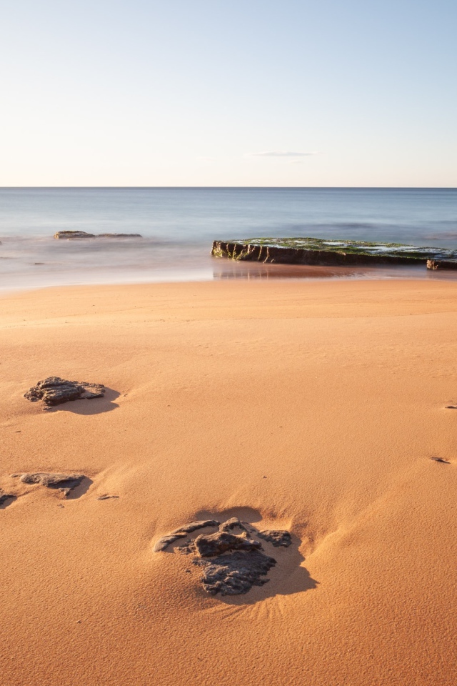 Камни в песке на берегу моря 