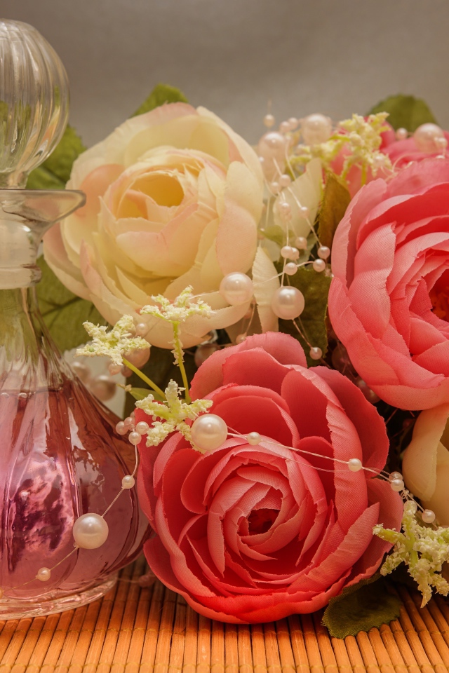 Красивый букет искусственных роз на столе с духами