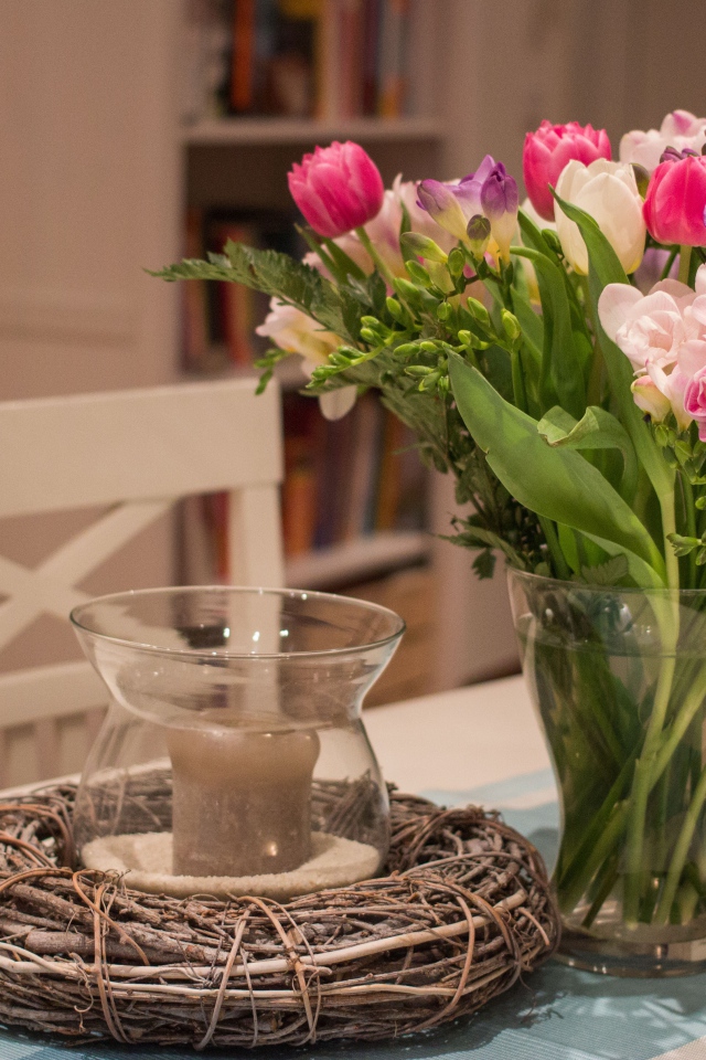 Красивый букет ярких цветов на столе со свечой