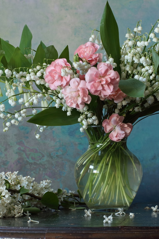 Красивый букет ландышей с розовыми цветами на столе с веткой сирени 