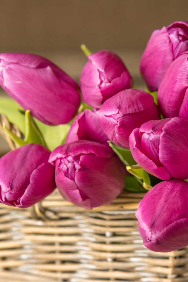 Букет красивых розовых тюльпанов в корзине на столе