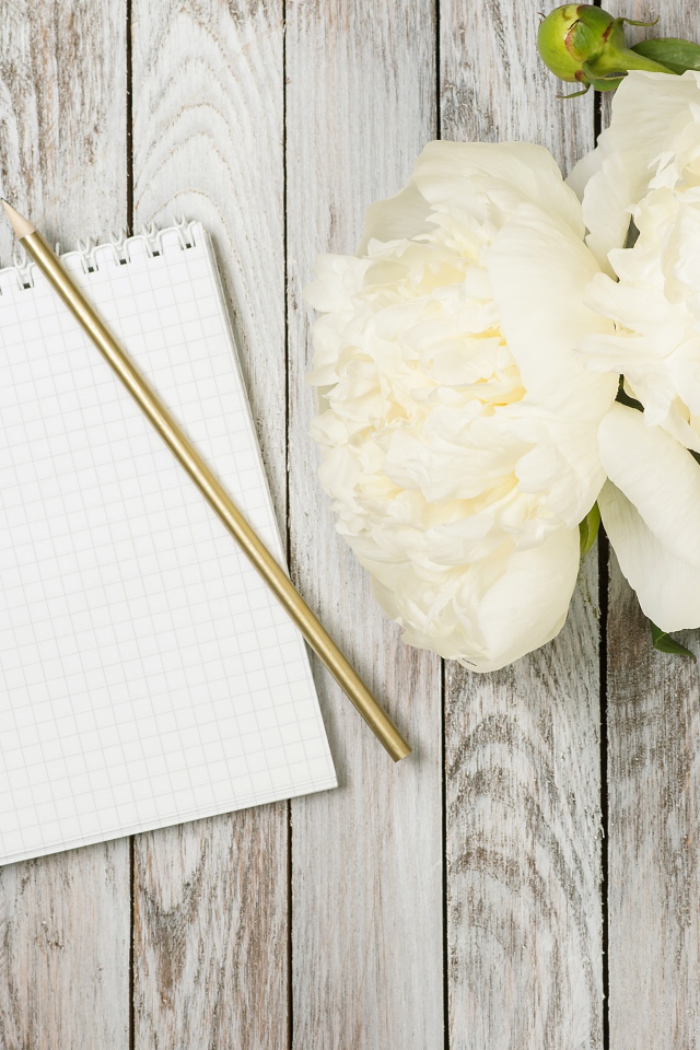 Букет белых пионов с блокнотом и ручкой на деревянном фоне 
