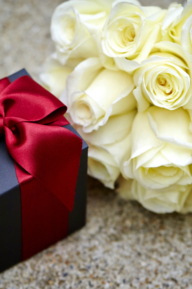 Букет белых роз с черным подарком на столе