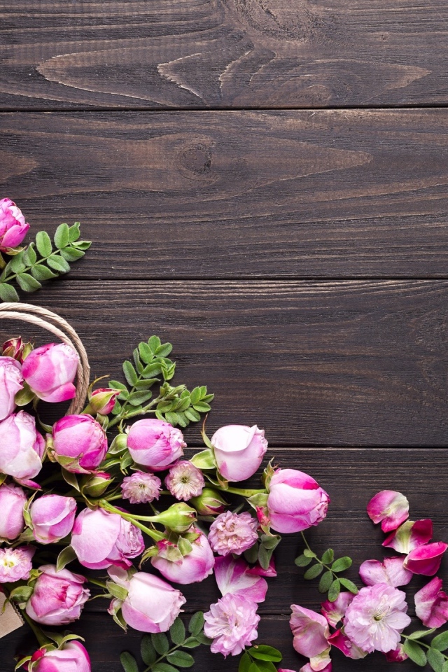 Цветки розовой розы с бумажным пакетом  на деревянном фоне