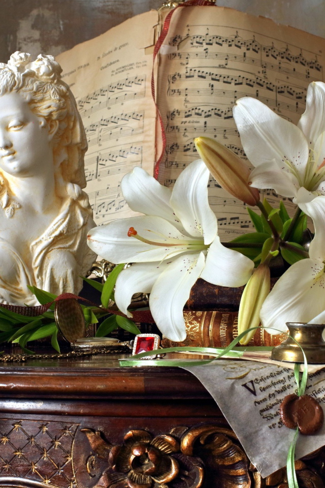 Белые лилии, статуя и ноты лежат на столе