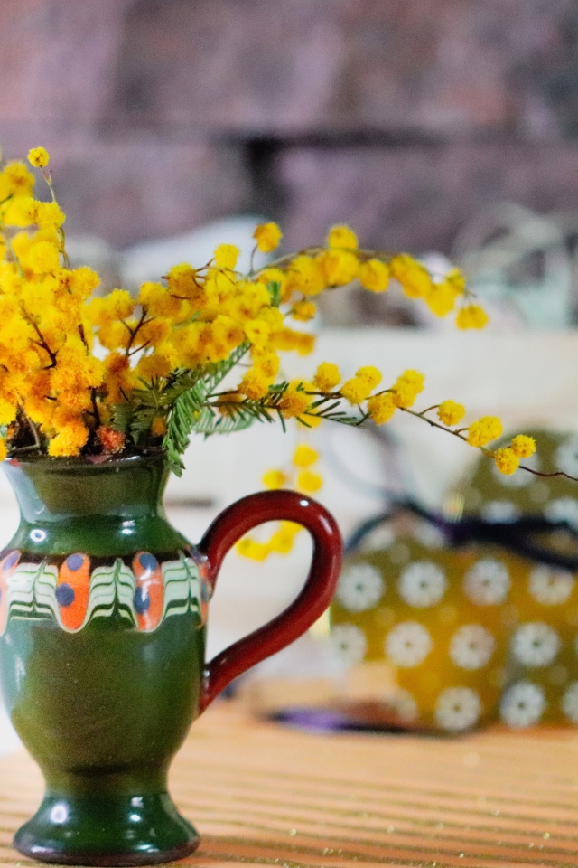 Желтые цветы мимозы в маленькой вазе на столе