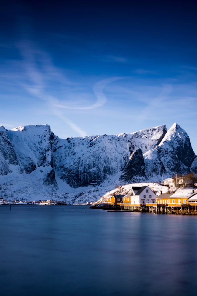 Красивый вид на дома у заснеженных гор под голубым небом 