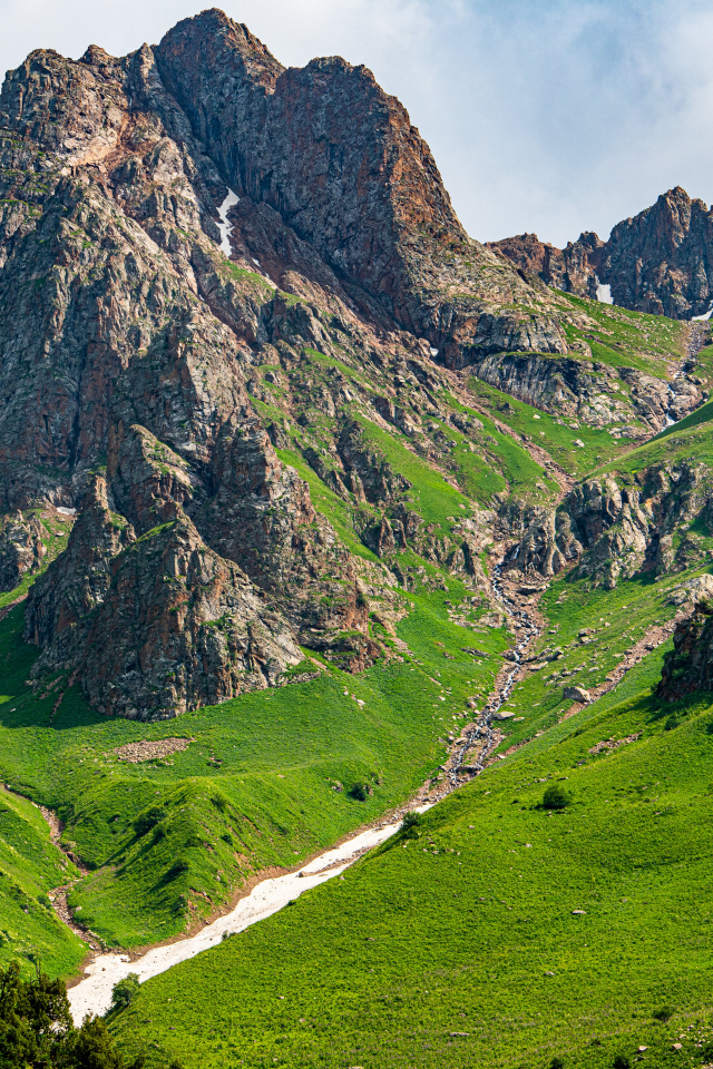 Большие каменные горы с зеленым ковром травы