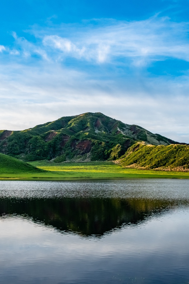 Красивый вид на покрытую зеленью гору под голубым небом у озера