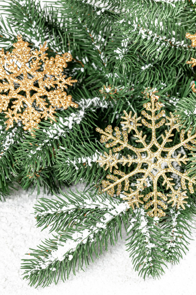 Золотистые снежинки и еловые ветки на снегу