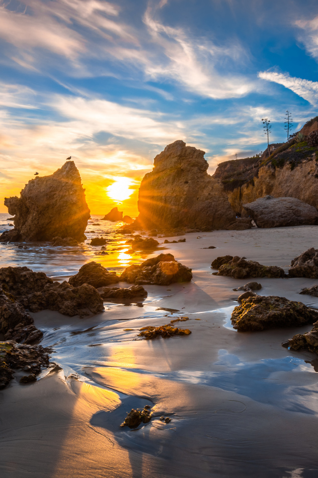 Яркий рассвет летнего солнца над скалами и океана