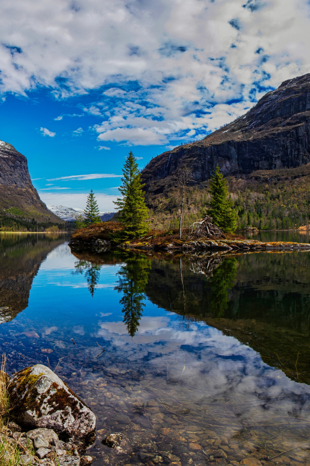 Остров среди озера у гор под красивым небом 