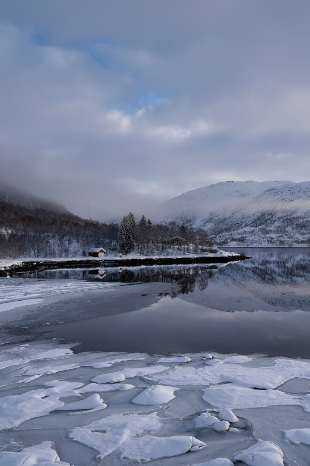 Покрытое льдом холодное озеро у гор в тумане