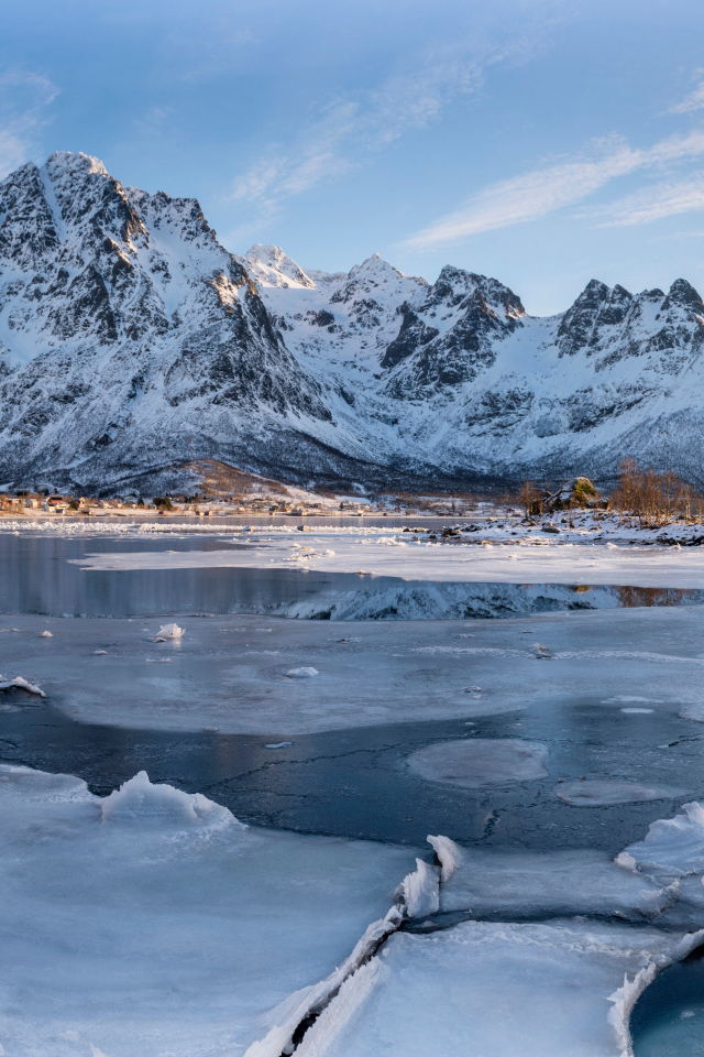 Покрытое льдом озеро у заснеженной горы