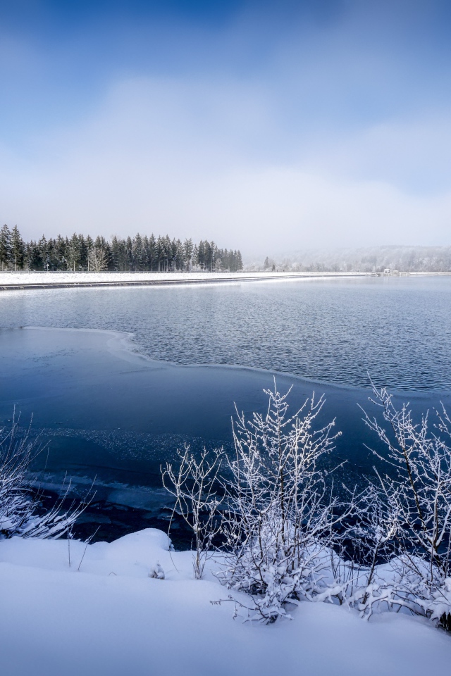 Покрытая льдом река  с заснеженными берегами зимой