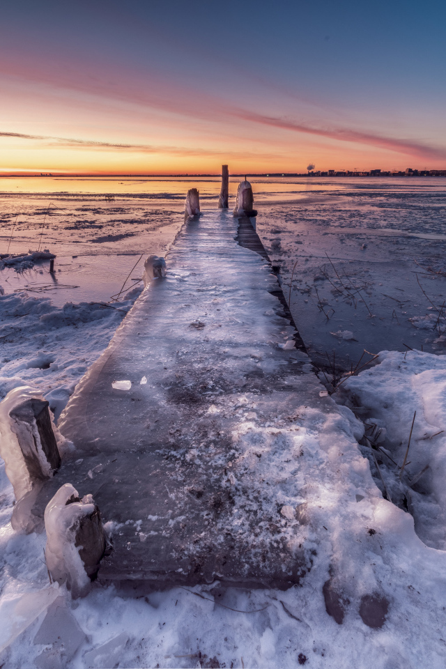 Покрытый льдом деревянный мост у озера 