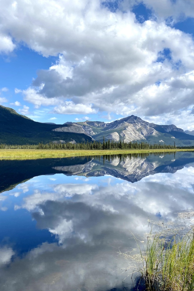 Небо с белыми облаками отражается в реке 