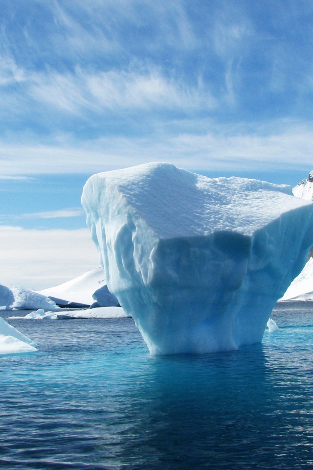 Большой голубой айсберг в воде у гор 