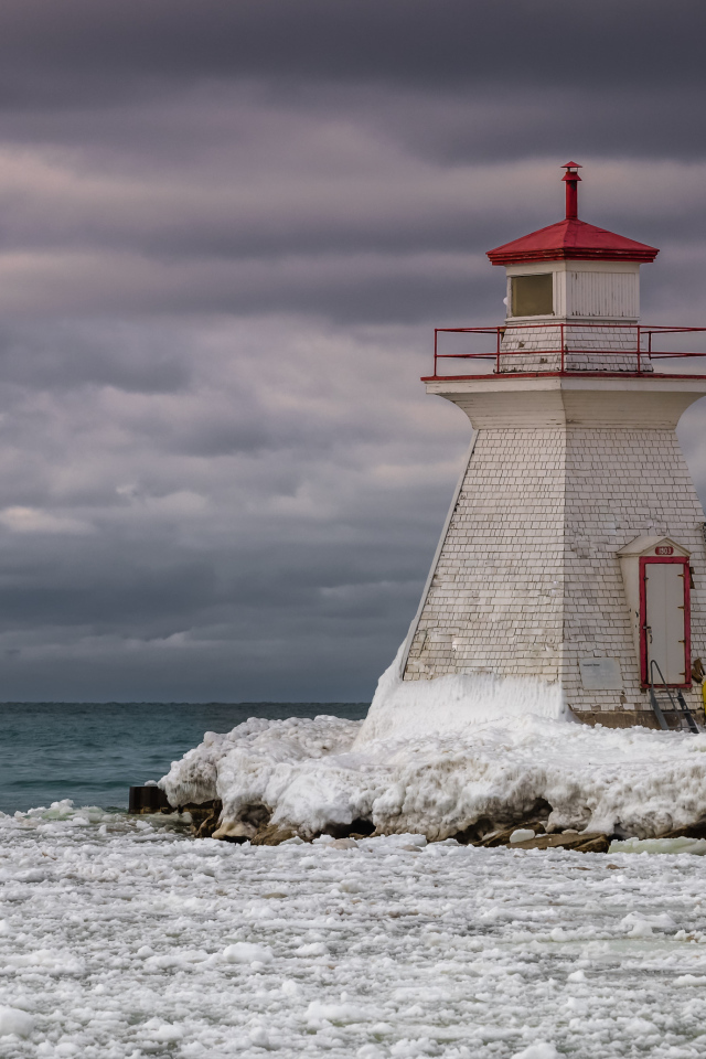 Маяк на покрытом льдом берегу у моря