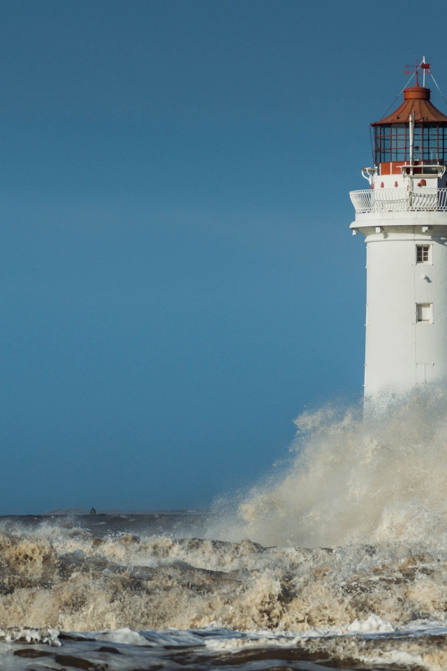 Бушующие белые волны бьются о маяк 