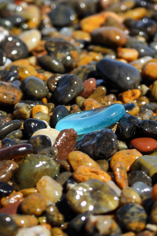 Гладкие разноцветные мелкие камни на пляже 