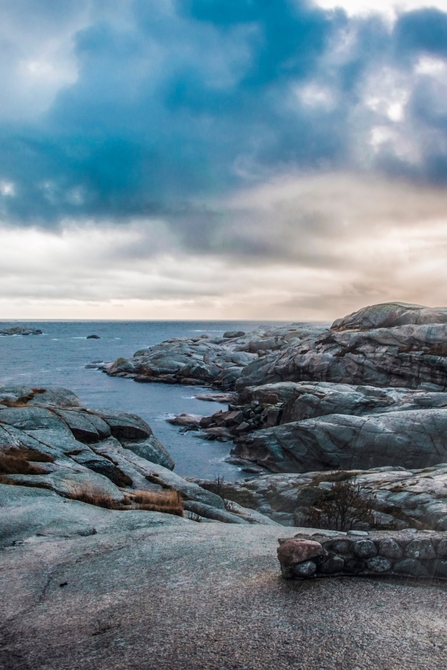 Каменный берег у тихого моря под черными облаками