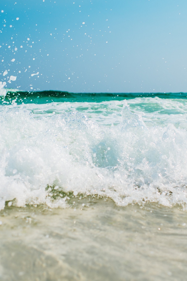 Белая морская пена бьется об берег 