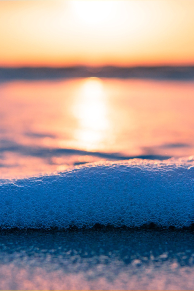 Белая морская пена с пузырям на закате