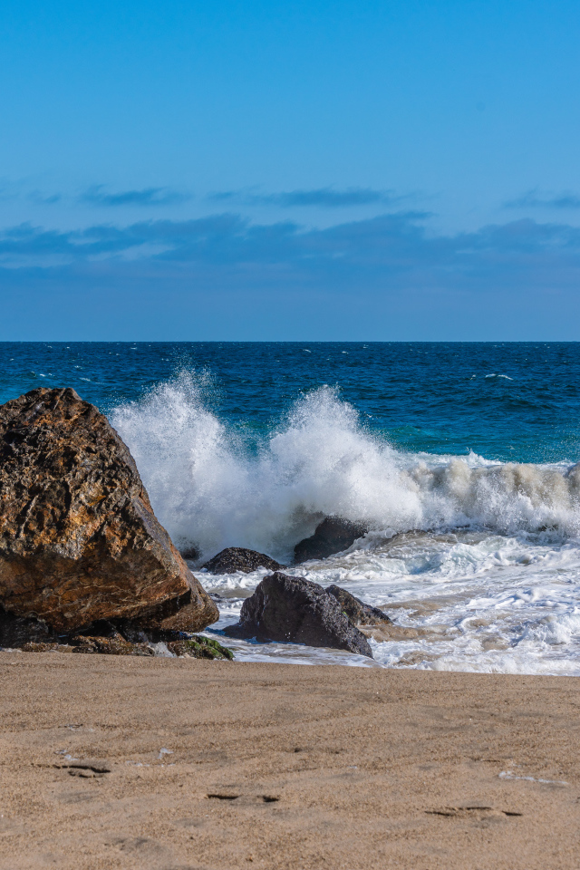 Белые морские волны бьются о большие камни на берегу