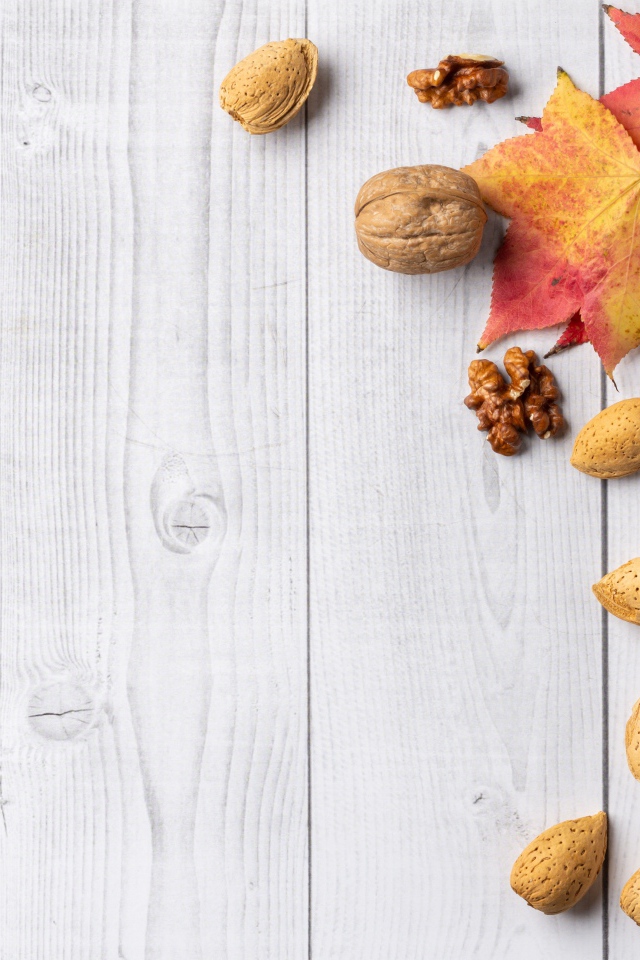 Опавшие листья и орехи на деревянном столе 