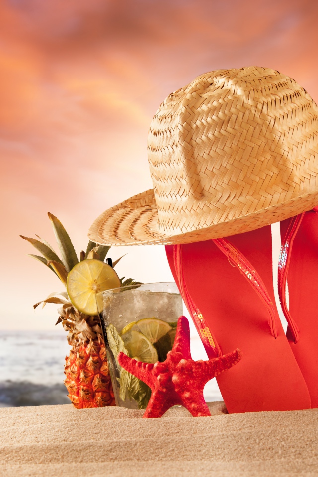 Шлепки, шляпа и коктейль с ананасом на пляже летом