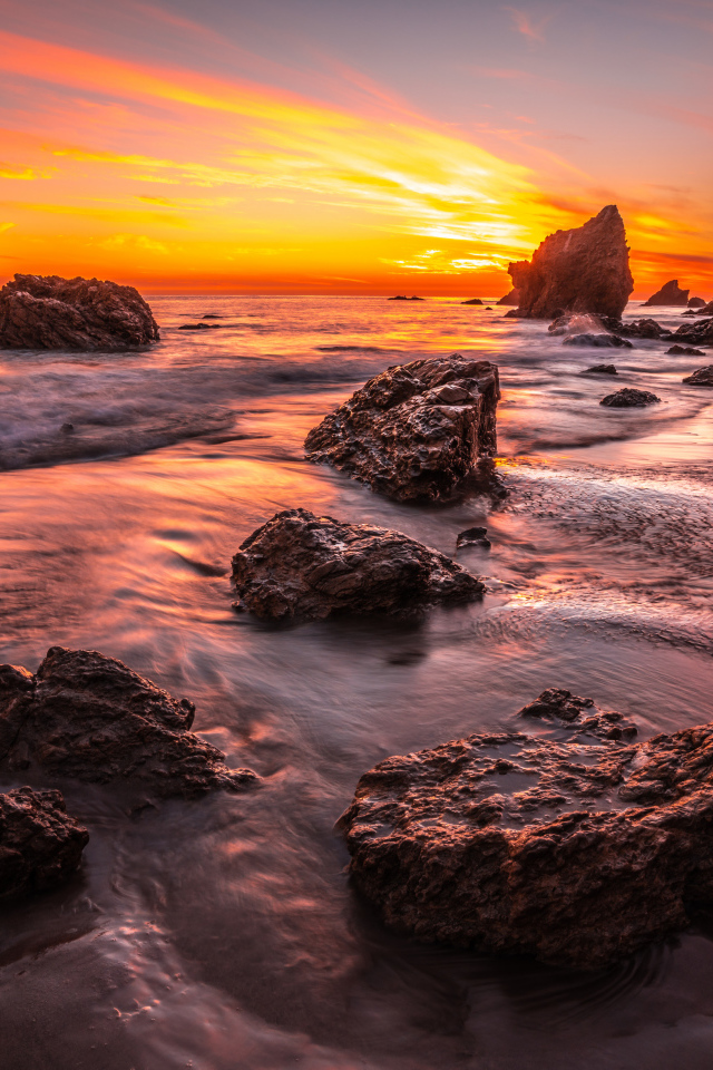 Красивый закат солнца на берегу моря с камнями 