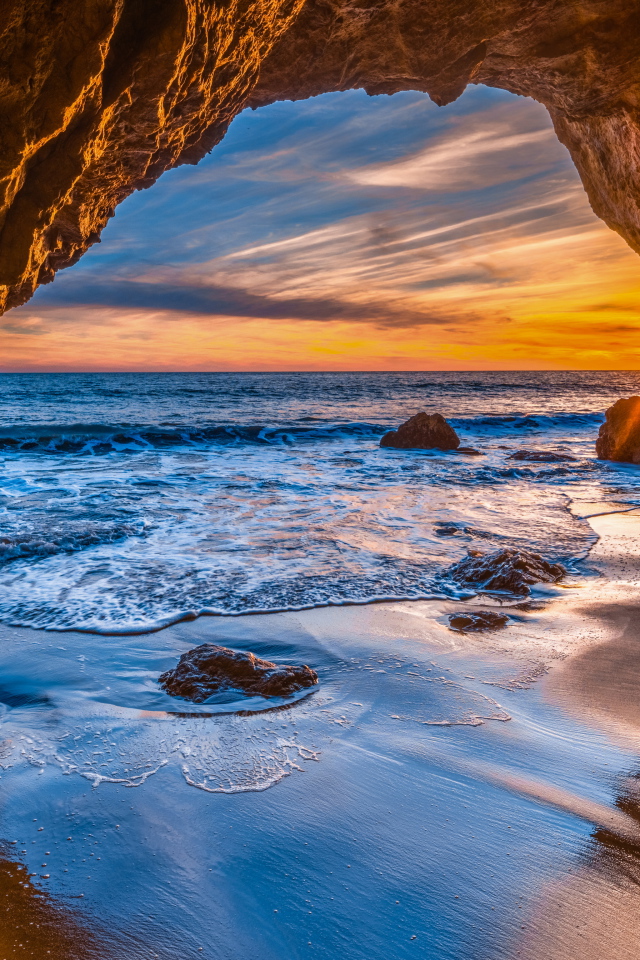 Закат солнца в каменной арке в море