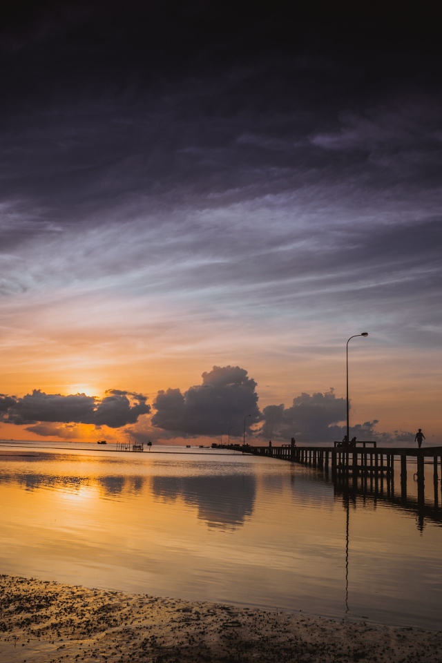 Деревянный мост на реке в лучах  солнца на закате