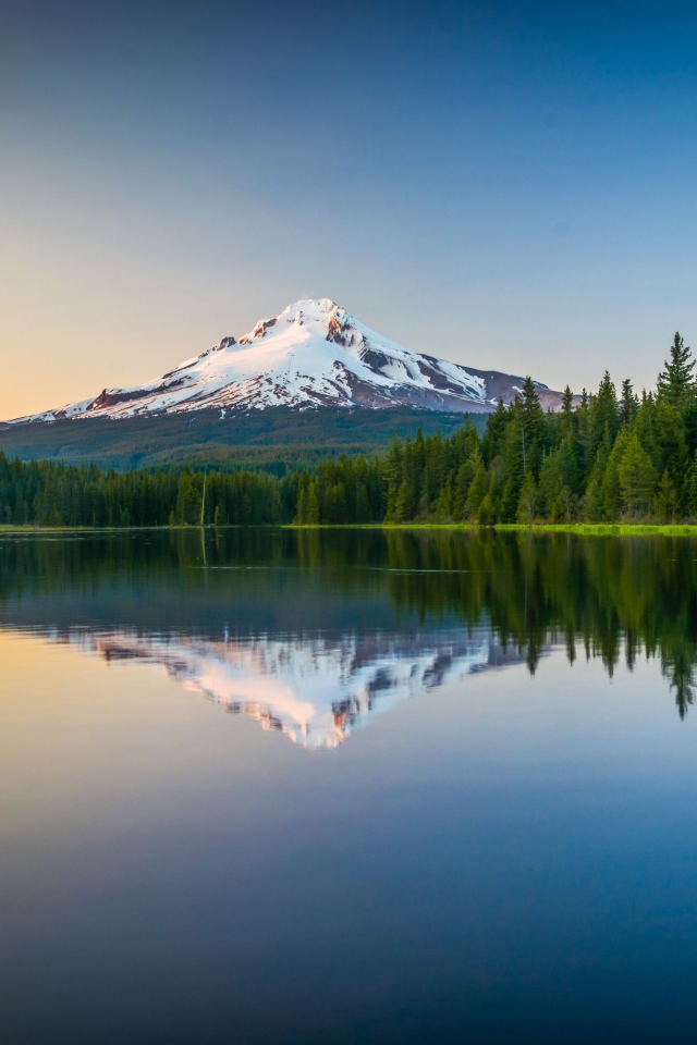 Заснеженная вершина вулкана отражается в холодной воде озера 