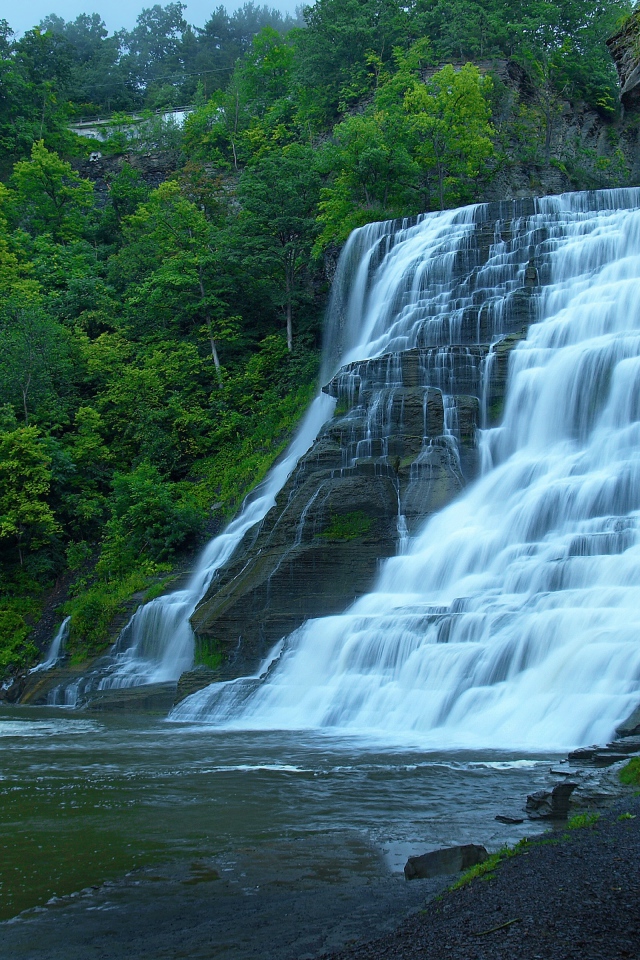 Красивый каскадный водопад с зелеными деревьями