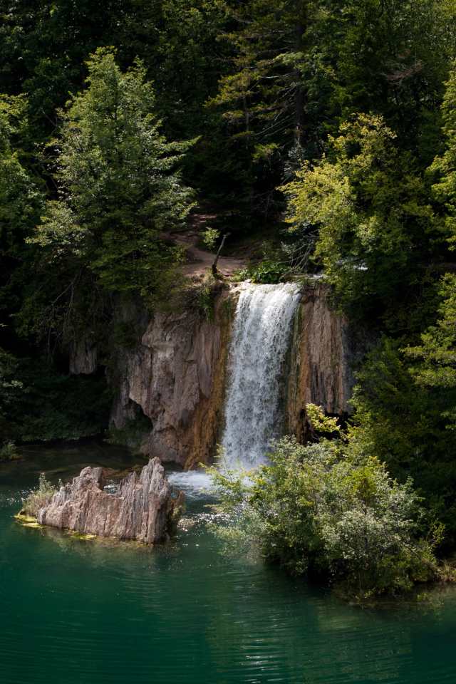 Водопад стекает со скалы в холодное озеро 