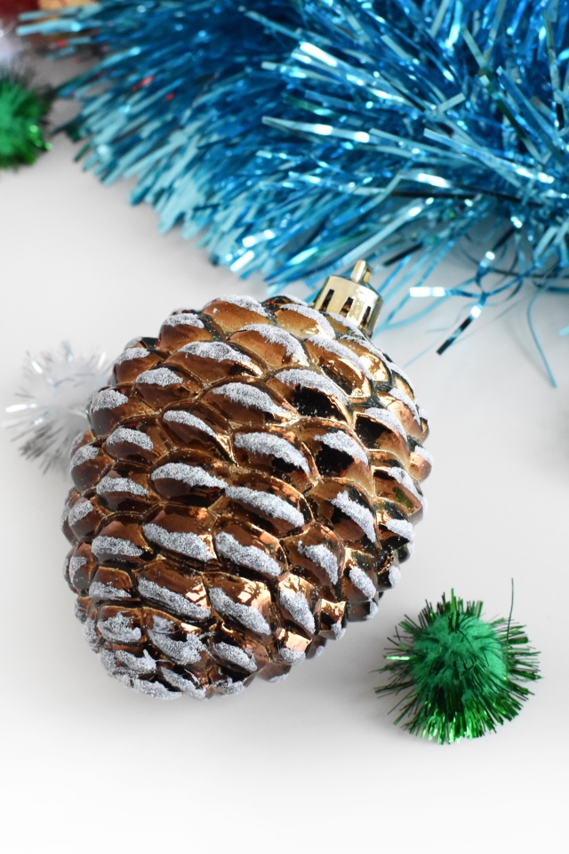 Елочная игрушка шишка с мишурой на белом фоне 